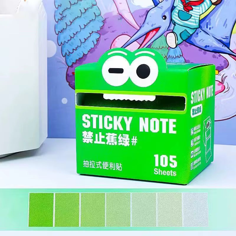 A green box of sticky notes with a cartoon frog face on top ,'STICKY NOTE' and '105 Sheets'. A row of six green color chips is shown along the bottom, likely indicating the note color variety.